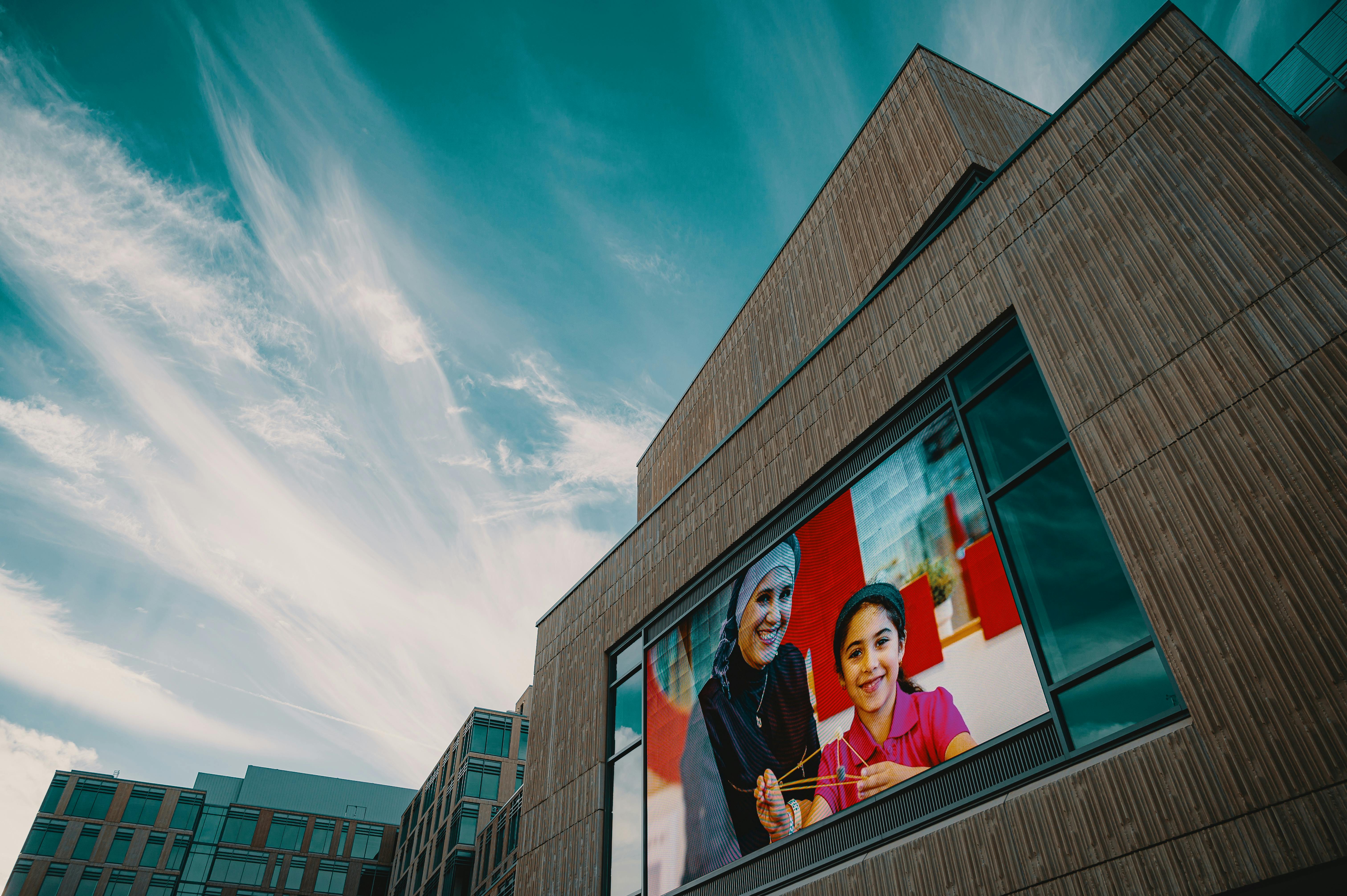 Modern building facade showcasing a large digital screen displaying a vibrant image against a blue sky.